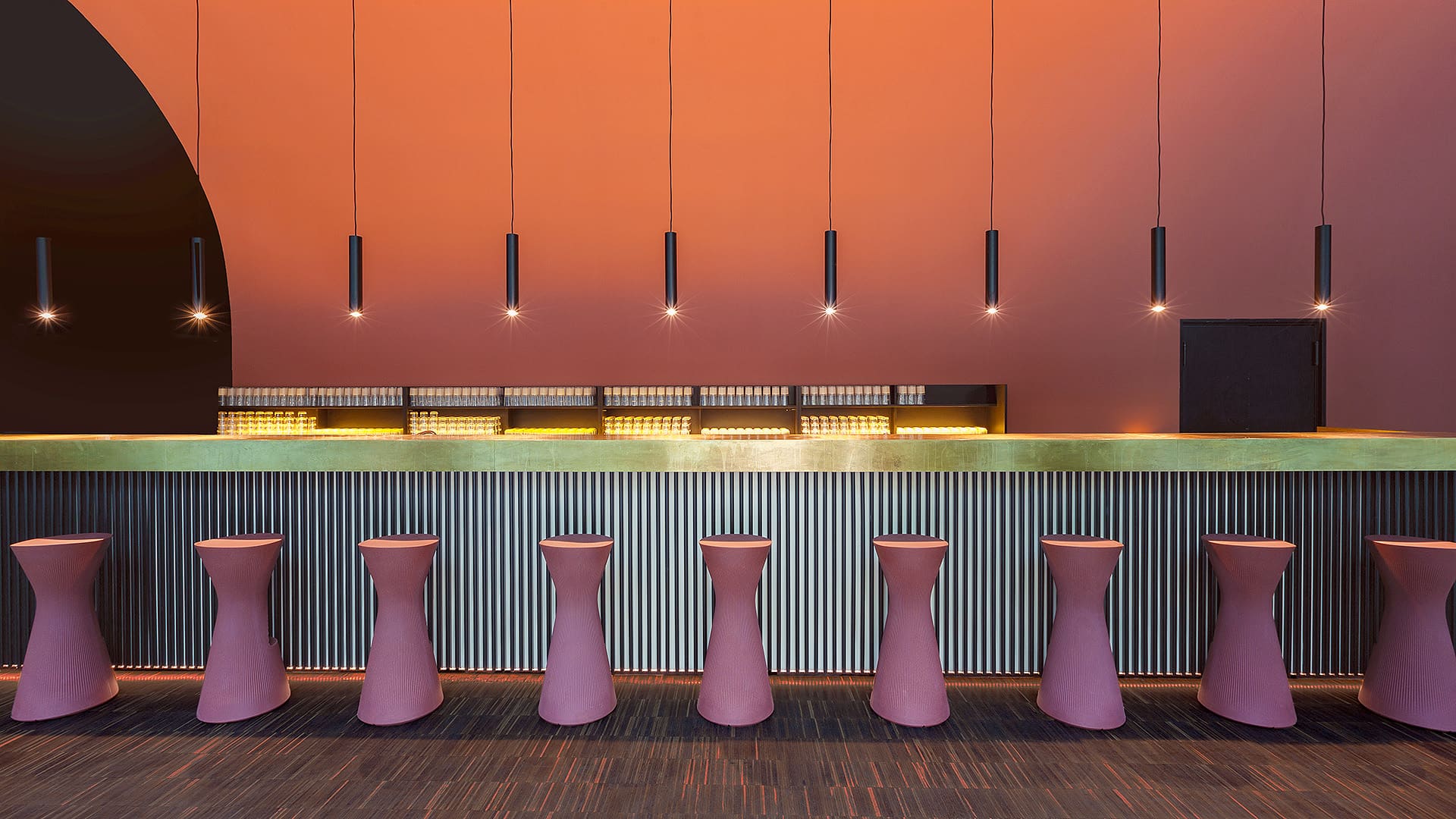 Ayoka Space: Bar mit Barhockern vor warmer Terracotta-Wand